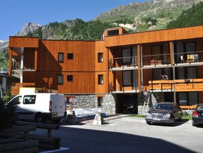 A modern multi-story building with wooden exterior walls, a stone base, and balconies. - Bright studio for 2 in Val d'Isère (Val-d'Isère)