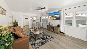 Un salon moderne avec un canapé, une table basse et une vue sur la plage grâce à de grandes fenêtres.