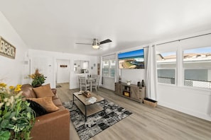 Ein modernes Wohnzimmer mit einer Couch, einem Couchtisch und Blick auf den Strand durch große Fenster.