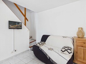 Ein Schlafzimmer mit einem Bett, einem Nachttisch aus Holz, einem an der Wand befestigten Fernseher und einer Treppe.