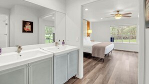 Un baño moderno con lavamanos dobles, un espejo grande y un ventilador de techo.