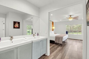 A modern bathroom with dual sinks, a large mirror, and a ceiling fan. - 16 Private Acres Near Wimberley Square | Hot Tub & Room for Groups (Wimberley)