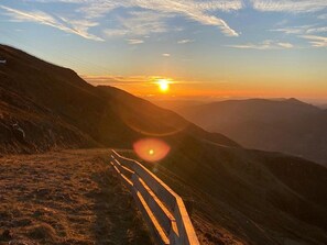 Ein Bergweg mit Holzzaun, der in Richtung Sonnenuntergang führt.