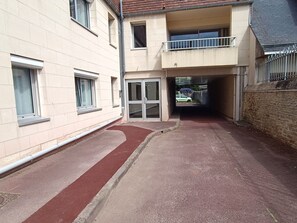 A narrow alleyway with a red bike lane, a gated entrance, and a building with a balcony. - Ground floor apartment - 4 guests (Courseulles-sur-Mer)