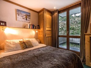 Une chambre à coucher avec un lit, une fenêtre avec des rideaux, une bibliothèque et un tableau accroché au mur.