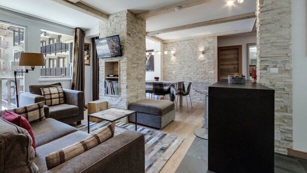 Un salon moderne avec un mur d’accent en pierre, une cheminée et un coin repas offrant une vue sur la ville.