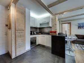 Eine moderne Küche mit Holzschränken, einer Mittelinsel und einer Wand als Steinakzent.