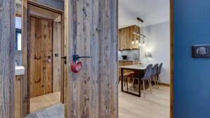 A modern kitchen with wooden cabinets, a dining area with a table and chairs, and a blue accent wall. - Renovated apartment near slopes - 5 guests (Val-d'Isère)