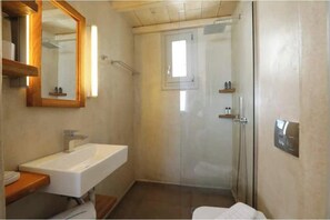 Ein Badezimmer mit Waschbecken, Spiegel, Dusche und Toilette.