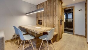 Eine moderne Küche mit einer Holztheke, vier Stühlen, einem eingebauten Backofen und einer hängenden Leuchte.