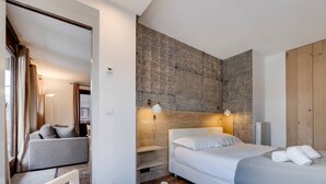 Ein modernes Schlafzimmer mit einem Bett, einer Couch und Holzboden.