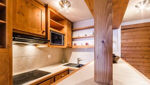 A modern kitchen with wooden cabinetry, a Bosch microwave, and a sink. - Apartment with slope views, 6 guests (Val-d'Isère)