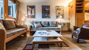 A cozy living room with a sofa, a coffee table, and a leather armchair. There are three framed pictures on the wall and a wooden cabinet. - Apartment with slope views, 6 guests (Val-d'Isère)