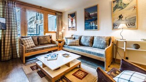 A cozy living room with a sofa set, a coffee table, and a view of mountains through large windows. - Apartment with slope views, 6 guests (Val-d'Isère)