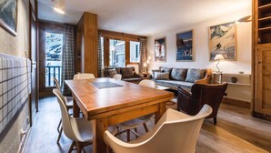 A cozy room with a wooden dining table, white chairs, a sofa, and a wooden cabinet. - Apartment with slope views, 6 guests (Val-d'Isère)