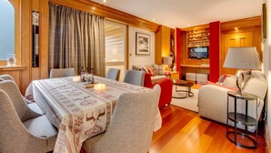 Een moderne woonkamer met een eethoek, houten lambrisering, een televisie en een open haard.