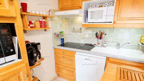A kitchen with wooden cabinets, a microwave, a dishwasher, and a coffee maker. - Charming apartment - 6 guests Saint-Jean-de-Sixt (Saint-Jean-de-Sixt)