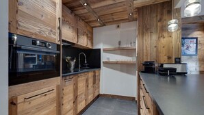 Een moderne keuken met houten kastjes, een zwart aanrecht en een De Dietrich oven.