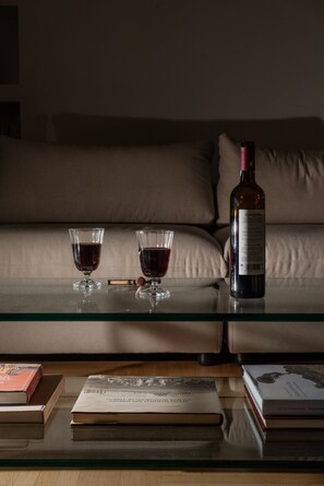 A glass table with two wine glasses and a bottle of wine, a book, and a book on a glass shelf. - Luxury 3BR & 3 Bathrooms Apt | Metro | By Museum (Athens)