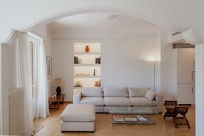A modern living room with a sofa, ottoman, and a glass coffee table. - Luxury 3BR & 3 Bathrooms Apt | Metro | By Museum (Athens)