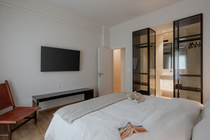 A hotel room with a bed, a bench, a TV, and a wardrobe with a mirror. - Luxury 3BR & 3 Bathrooms Apt | Metro | By Museum (Athens)
