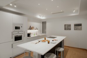 A modern kitchen with white cabinetry, a central island, and a dining area. - Luxury 3BR & 3 Bathrooms Apt | Metro | By Museum (Athens)
