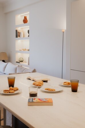 Ein Esstisch mit Tellern voller Kekse und Tee, ein Buch und eine Lampe.