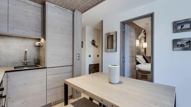 Une cuisine moderne avec des meubles en bois, un évier encastré et une grande table en bois.