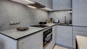Une cuisine moderne avec des meubles de couleur grise, un four encastré et un plan de travail agrémenté d’un saladier.