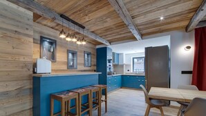 Een moderne keuken met blauwe kastjes, houten aanrecht en een eethoek met een houten tafel en krukken.