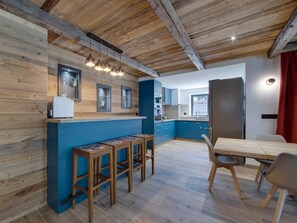 Eine moderne Küche mit blauen Schränken, Holz Arbeitsplatten und einem Essbereich mit Holztisch und Hockern.