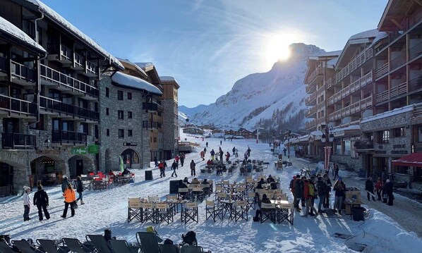 A snow-covered town square with outdoor seating and buildings with balconies. - Ski-in/ski-out apartment, parking - 4-6 guests (Val-d'Isère)