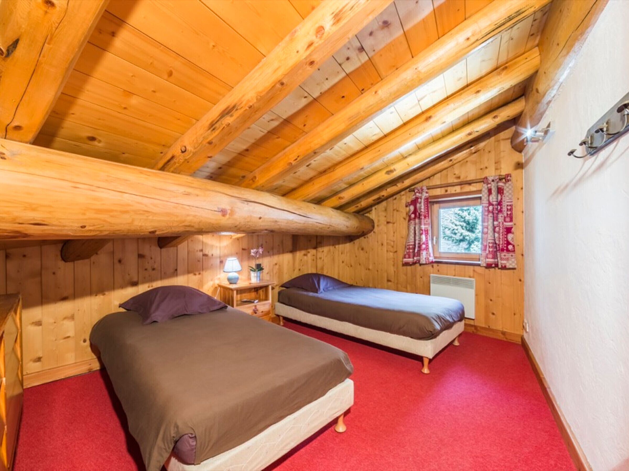 A cabin with two beds, a window with curtains, a lamp, and a radiator.