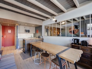 A modern kitchen with a wooden island, bar stools, and a red door. - Ski-in ski-out duplex, 3 bedrooms - 6 guests (Val-d'Isère)