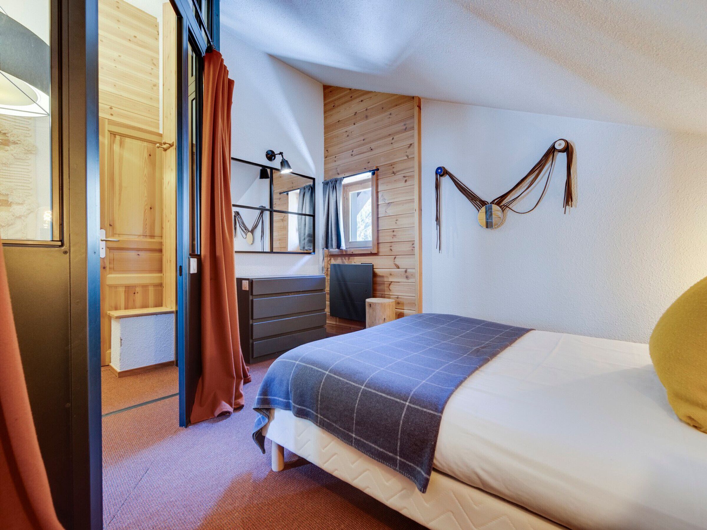 A bedroom with a bed, a dresser, a mirror, and a window.