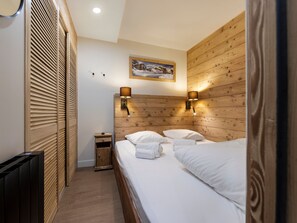 Ein Hotelzimmer mit einem hölzernen Kopfteil, zwei Nachttischlampen, einem Bild über dem Bett, einem kleinen Nachttisch und einer Heizung.