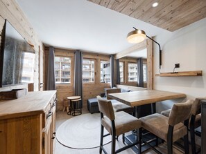Ein modernes Interieur mit Holzwänden, einem runden Esstisch und einem großen Fenster mit Blick auf die Stadt.