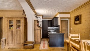 Une cuisine rustique avec des meubles en bois, un îlot central et un coin repas comprenant une table et des chaises en bois.