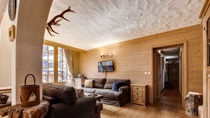 Une pièce confortable, aménagée comme un chalet, avec un intérieur en bois, un canapé, une table basse et une cheminée.