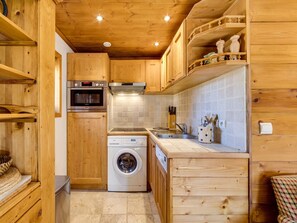 A compact kitchen with wooden cabinets, a Bosch oven, a washing machine, and a sink. - Bright apartment with parking - 4 guests (Val-d'Isère)