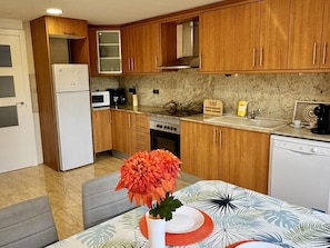 A kitchen with wooden cabinets, a refrigerator, a microwave, a stove, and a dishwasher.
