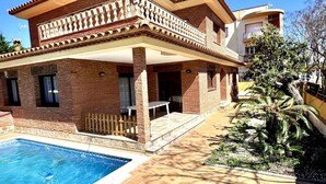 A two-story house with a swimming pool, a patio, and a garden.