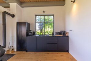 Eine moderne Küche mit großem Fenster, dunklen Schränken und Holzboden.