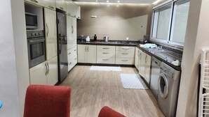 Eine kompakte Küche mit Mikrowelle, Backofen, Kühlschrank und Waschmaschine.