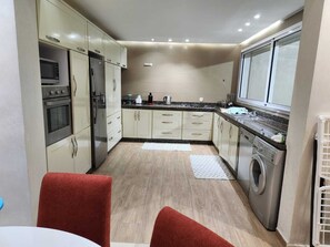 A compact kitchen with a microwave, oven, refrigerator, and washing machine.