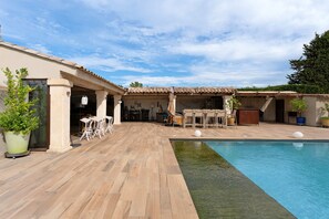 A poolside area with a wooden deck, outdoor seating, and a clear blue pool. - Holiday Home "Bastide Neuve en Provence" with Private Pool, Terrace & Wi-Fi (Caumont-sur-Durance)