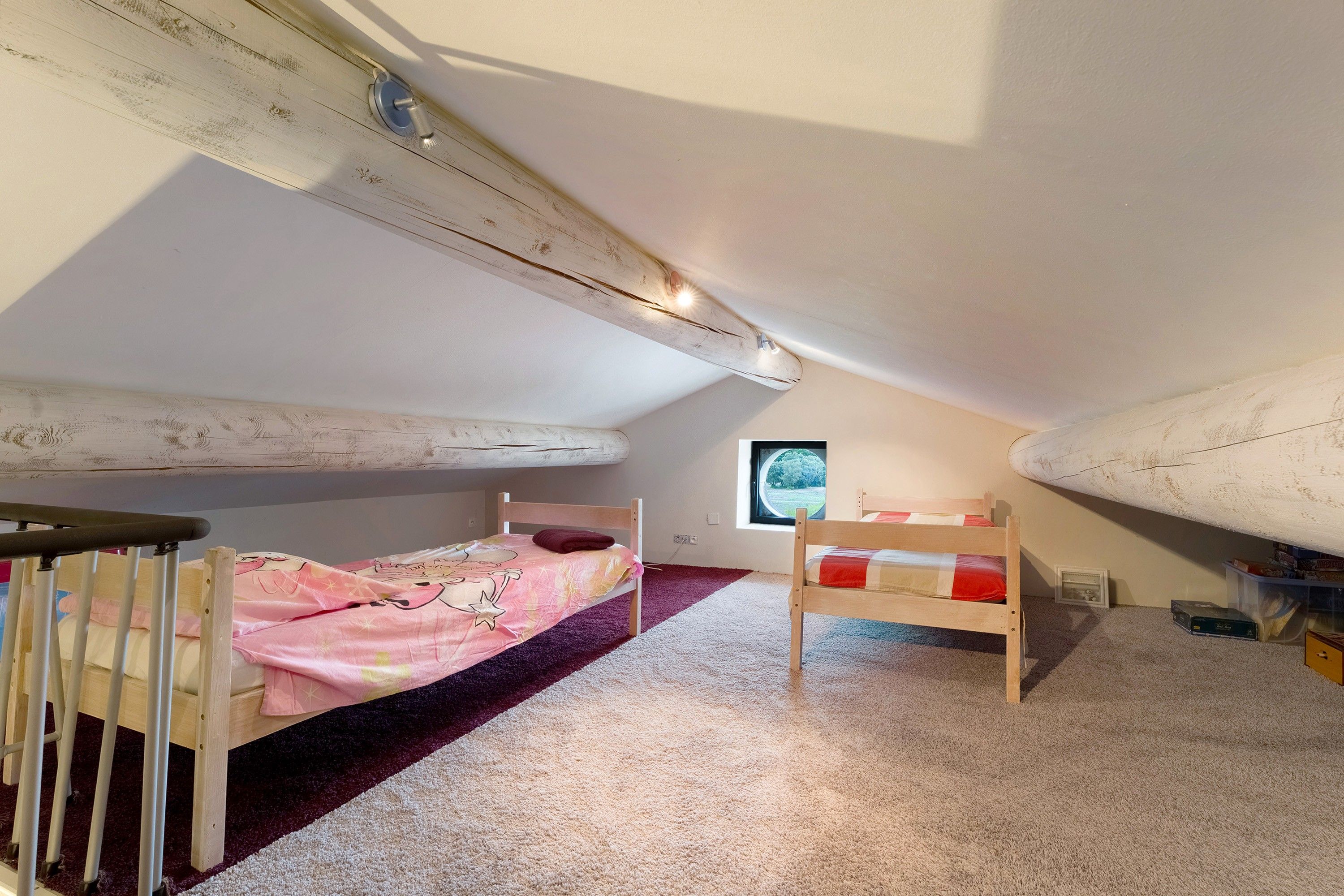 Ein Kinderzimmer mit zwei Etagenbetten, einem Fenster mit Blick und einem Holzbalken an der Decke.