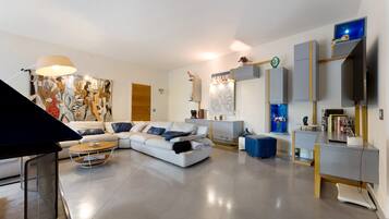 A modern living room with a sectional sofa, a coffee table, and a flat-screen TV mounted on the wall.