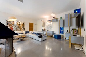 A modern living room with a sectional sofa, a coffee table, and a flat-screen TV mounted on the wall.