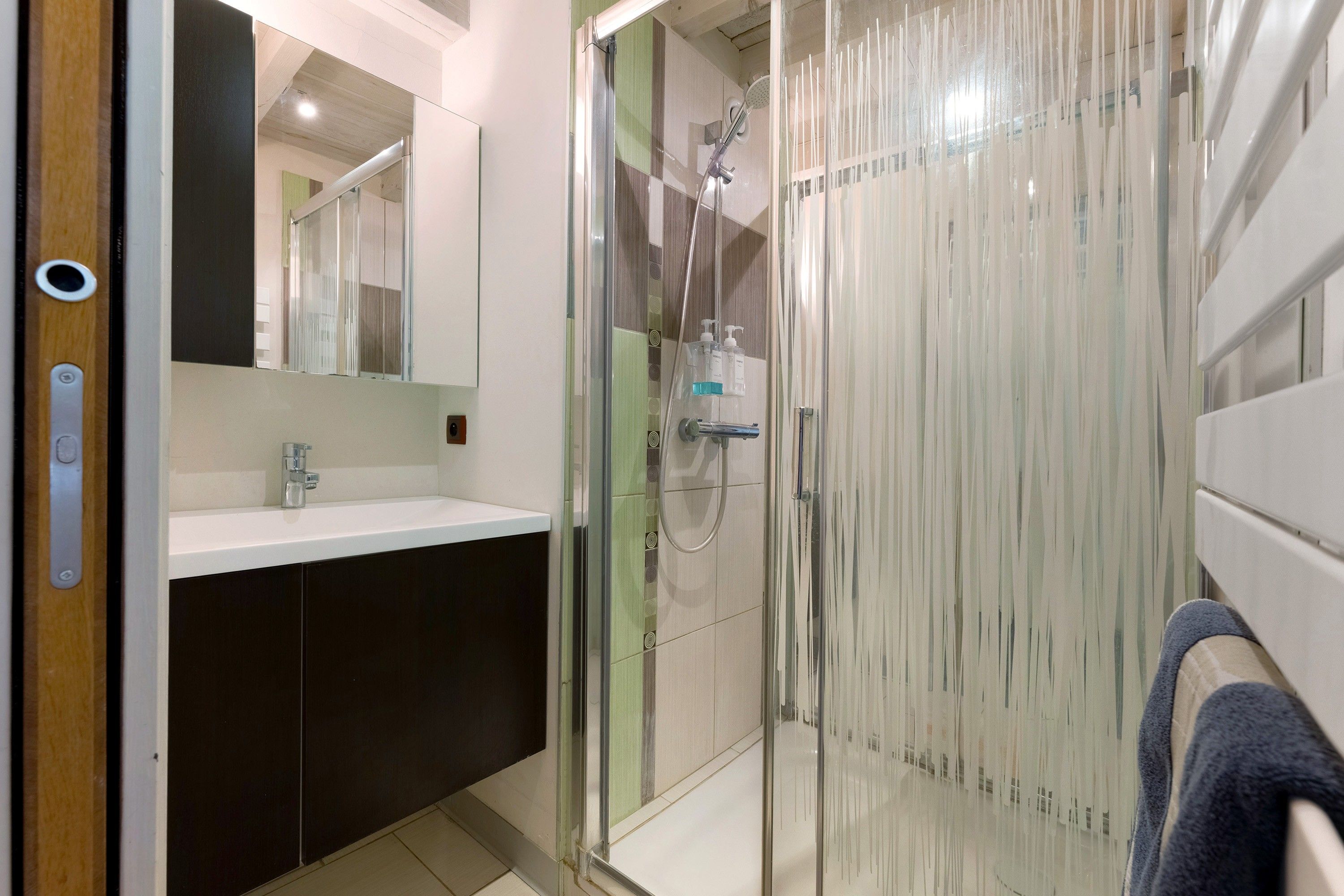 Une salle de bain moderne avec une douche à parois de verre, un lavabo et un miroir.